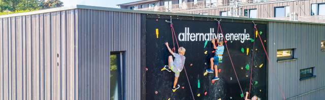 Luftaufnahme bei dem drei Kinder an der Kletterwand des Hotels Strandkind empor klettern