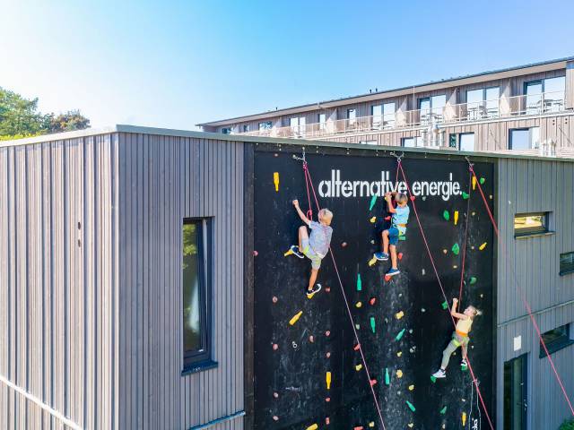 Luftaufnahme bei dem drei Kinder an der Kletterwand des Hotels Strandkind empor klettern