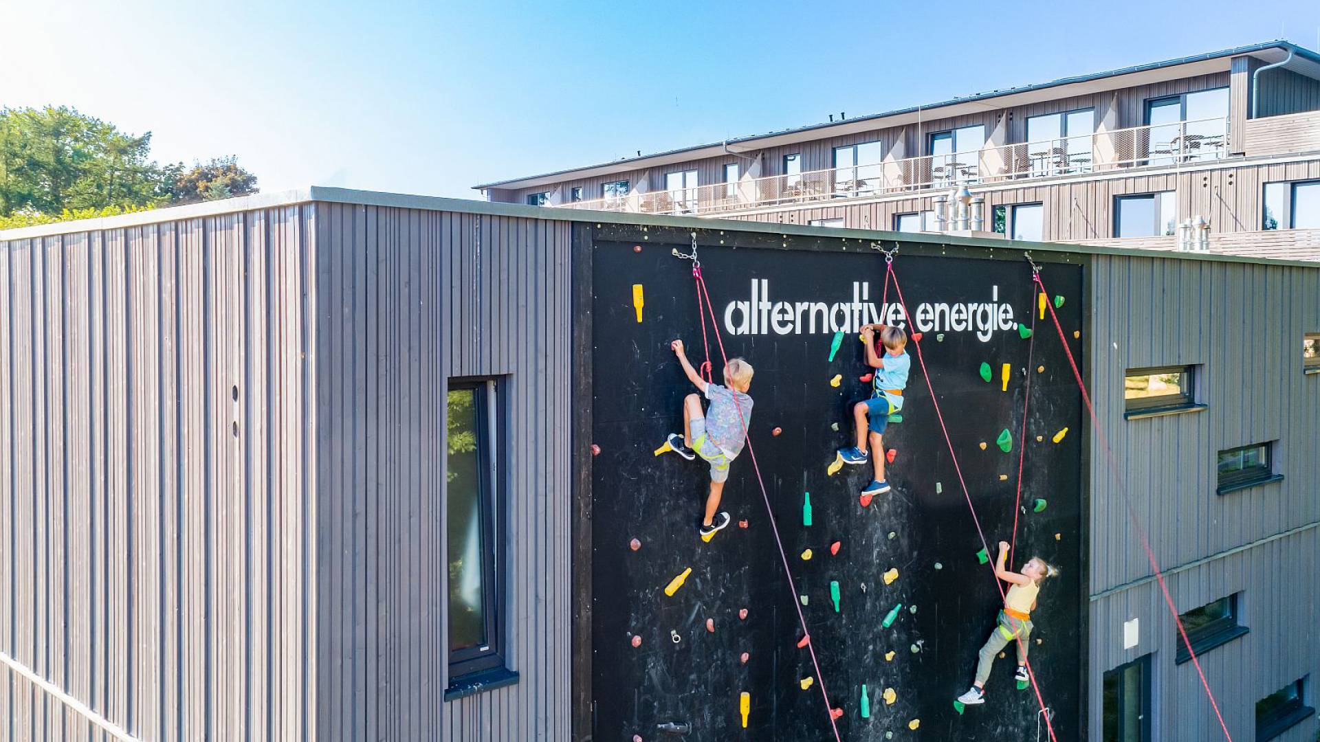 Luftaufnahme bei dem drei Kinder an der Kletterwand des Hotels Strandkind empor klettern